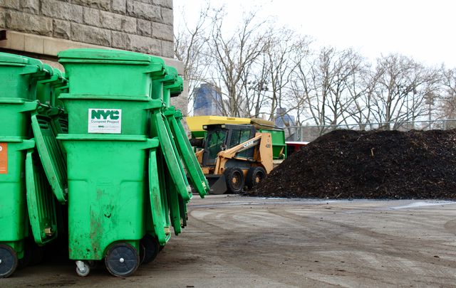 Green composting bins sit next to a pile of compost at the Big Reuse composting site.